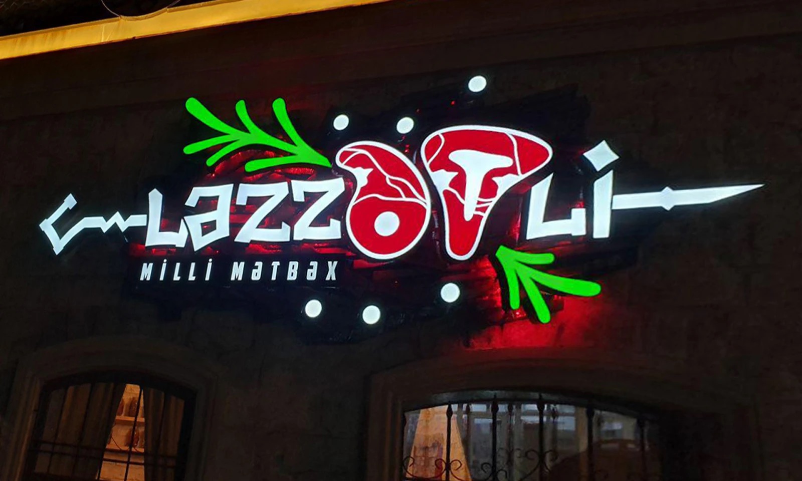 The same sign at night, glowing red and green above the entrance