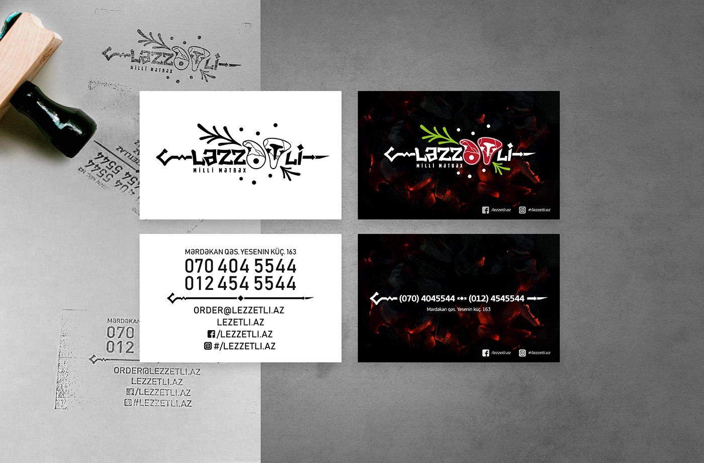 A rubber stamp beside white and black business cards and stamped marks